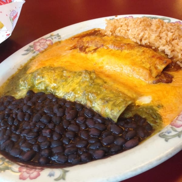 Jalisco's Mexican Restaurant's enchiladas with green and red sauce, black beans, and rice on a floral plate.