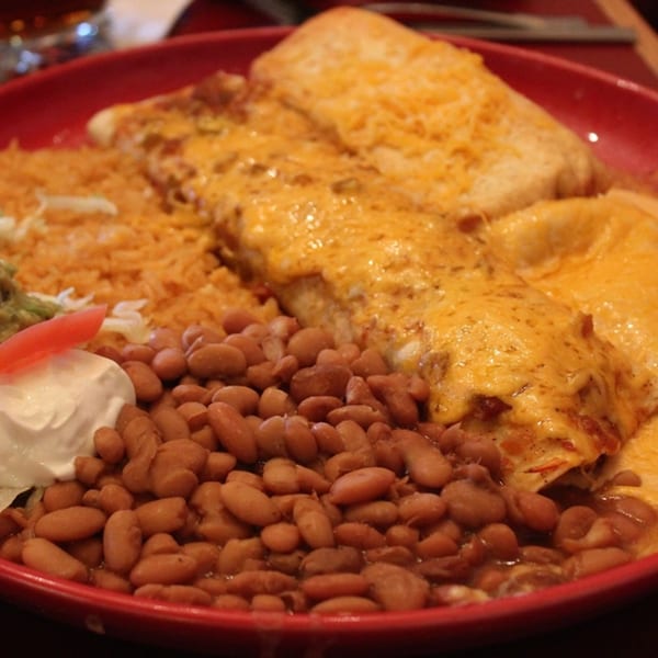 Jalisco's Mexican Restaurant's enchiladas with melted cheese, rice, beans, sour cream, and a tomato slice.